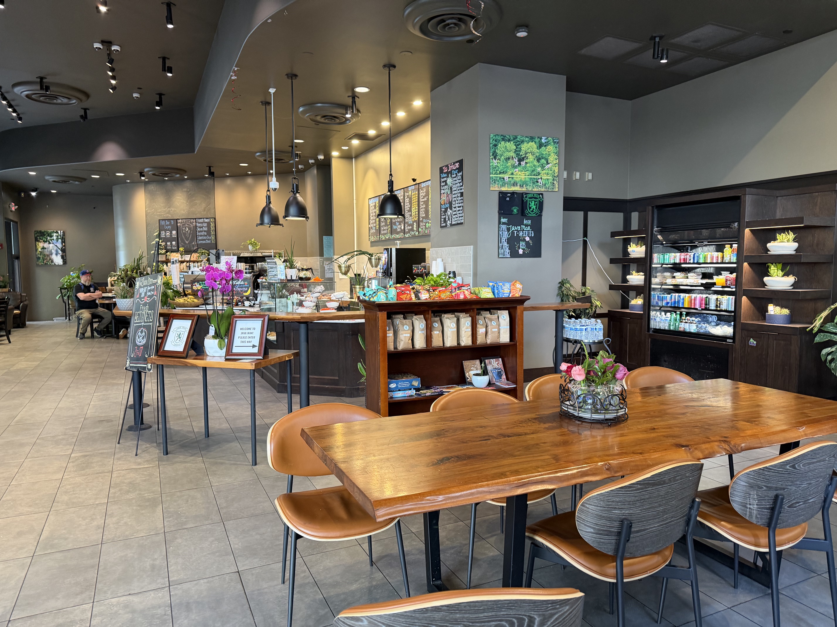 Cozy interior of JavaMan Coffee with wooden tables and plants